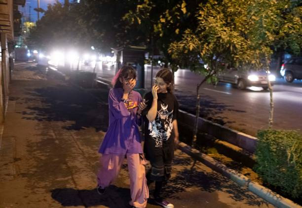 Hai nữ sinh Iran vừa đi bộ vừa trò chuyện vui vẻ ở trung tâm thủ đô Tehran tối 8/6/2023.