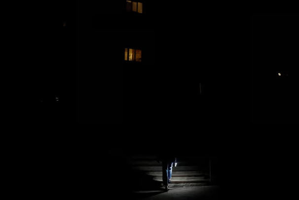 Một cư dân sử dụng đèn pin để soi đường đến cửa hàng tạp hóa.