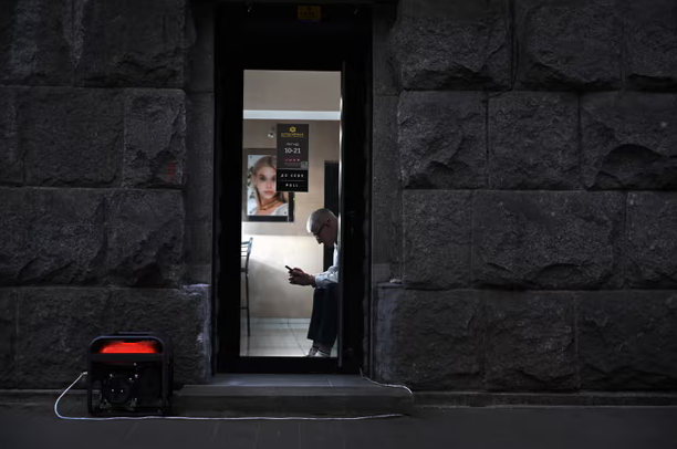 Một nhân viên cửa hàng trang sức ngồi chờ khách hàng, bên ngoài cửa hàng là máy phát điện.