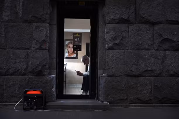 Một nhân viên cửa hàng trang sức ngồi chờ khách hàng, bên ngoài cửa hàng là máy phát điện.