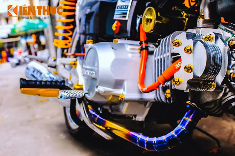 Full ốc vàng đầu lòng, lốc máy, tăng áp NGK mạnh mẽ cùng cổ pô khò màu titan bắt mắt. Khối động cơ 100 cc gốc của chiếc Honda Super Dream vẫn được người chơi để nguyên.