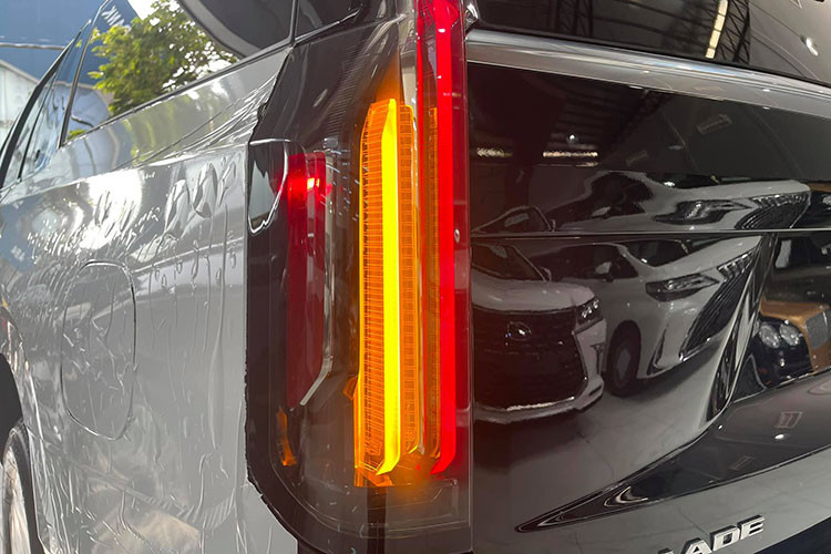 Cadillac Escalade 2021 bản ESV đặc biệt lực lưỡng khi nhìn ngang thân xe nhờ bộ mâm màu hợp kim với kích thước đến 22 inch. Đặc biệt, phần trụ C-D của xe kéo dài sử dụng kính đen giúp xe trở nên dài hơn, cùng với đó phần nẹp crom ở trụ C nổi bật. Đuôi xe sở hữu dải đèn hậu LED kéo dài từ trần xe và kết thúc gần cửa khoang hành lý, ống xả đôi 2 bên cân đối.