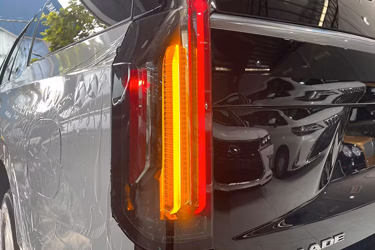 Cadillac Escalade 2021 bản ESV đặc biệt lực lưỡng khi nhìn ngang thân xe nhờ bộ mâm màu hợp kim với kích thước đến 22 inch. Đặc biệt, phần trụ C-D của xe kéo dài sử dụng kính đen giúp xe trở nên dài hơn, cùng với đó phần nẹp crom ở trụ C nổi bật. Đuôi xe sở hữu dải đèn hậu LED kéo dài từ trần xe và kết thúc gần cửa khoang hành lý, ống xả đôi 2 bên cân đối.