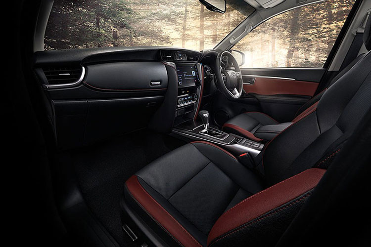 Bước vào bên trong Toyota Fortuner Commander 2022, người lái được chào đón bằng không gian nội thất màu đen phối đỏ tương phản, tăng vẻ thể thao cho xe. Ghế và mặt táp-lô đều đi kèm chỉ khâu màu đỏ.