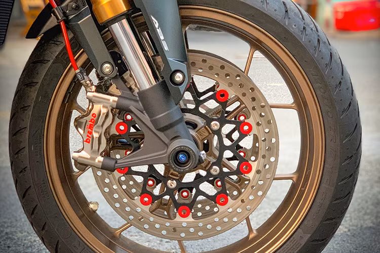 Ở phía dưới, hệ thống giảm xóc up-side-down màu vàng nguyên bản được giữ lại, toàn bộ hệ thống phanh đều được thay mới. Cụ thể, xe được trang bị hai kẹp phanh Brembo Nickel GP4RX 4 piston đi kèm đĩa phanh kép bằng nhôm CNC nhuộm đỏ và chống đổ bánh trước Evotech.