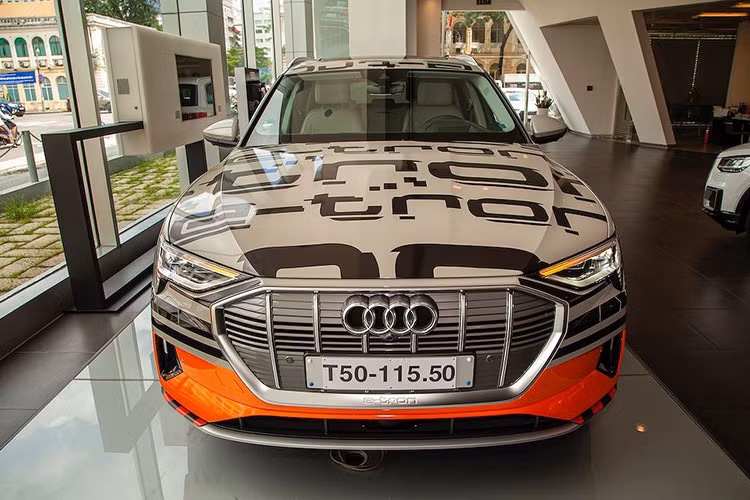 Ở phần đầu xe, toàn bộ lưới tản nhiệt có màu xám bạch kim – nhận diện cho mẫu xe chạy hoàn toàn bằng điện. Ở cạnh dưới của đèn pha LED ma trận, 4 thanh ngang trong hệ thống đèn chiếu sáng ban ngày tạo nên nhận diện đặc trưng cho e-tron. Lần đầu tiên các thanh ngang này được tích hợp trực tiếp vào đèn pha. Thiết kế đặc biệt cho phần ngưỡng cửa với phần ốp đen hiển thị vị trí pin.