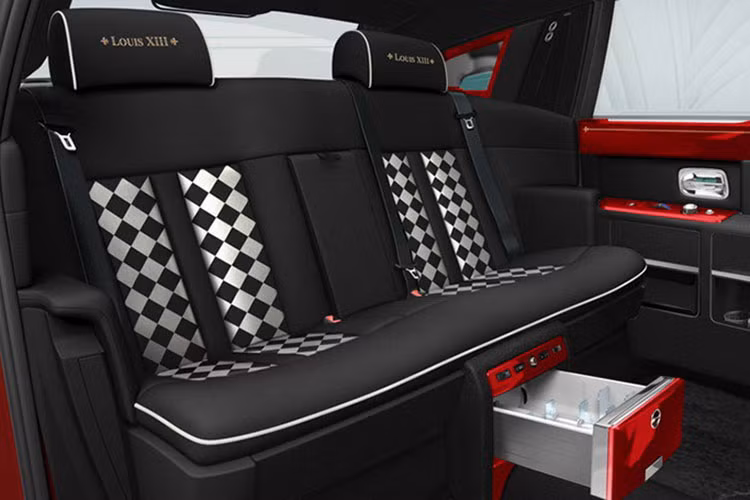 Nội thất bên trong cũng có màu chủ đạo là đỏ tươi giống bên ngoài. Logo Rolls Royce vẫn được gắn ở đuôi xe. Ghế ngồi được sản xuất từ da thật cao cấp màu đen. Riêng ghế sau có điểm nhấn caro đen trắng khá lạ mắt.