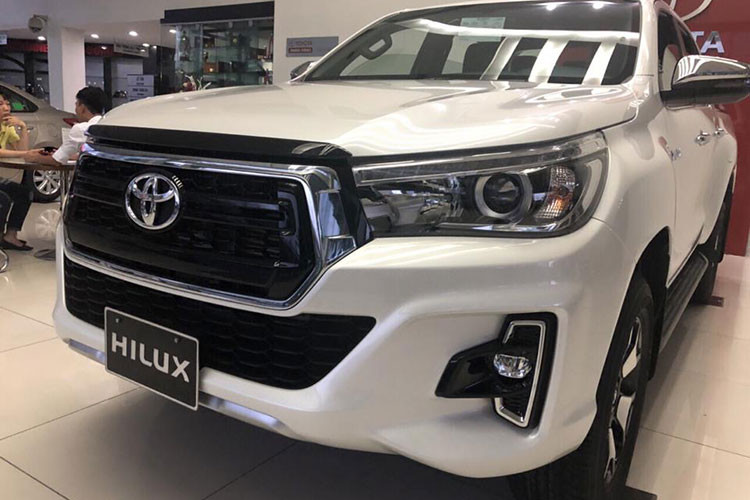 Điểm nhấn trên Hilux phiên bản 2018 này là đèn pha LED có tạo hình giống với phong cách của chiếc Toyota Tahoma tại thị trường Mỹ. Phần đầu xe - lưới tản nhiệt hình lục giác được làm mới với màu đen bóng cùng viền mạ crôm thể thao, so với đời cũ thì lưới tản nhiệt có kích thước lớn hơn và thiết kế thẳng đứng, mạnh mẽ hơn.