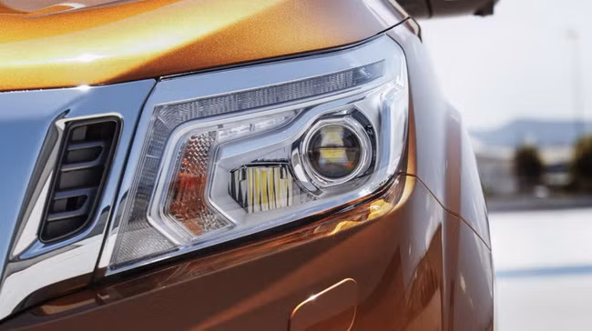 Nissan Navara NP300 phiên bản Châu Âu vẫn sử dụnglưới tản nhiệt dạng chữ V được sơn chrome đặc trưng, đèn pha projector tích hợp đèn LED và đèn xi-nhan tích hợp trên gương.