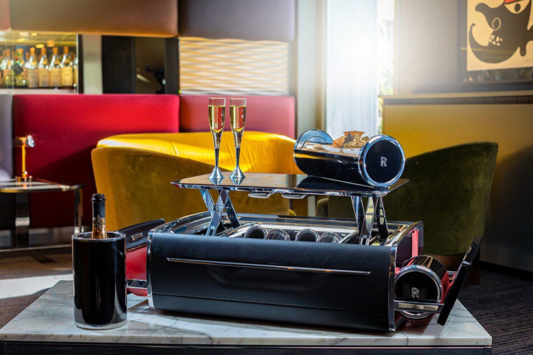 Không chỉ có thể, chiếc vali có võng treo bên sườn mà tự động mở ra để hé lộ hai hộp giữ mát sâm-panh được chế tạo từ sợi carbon và nhôm oxít hóa anốt màu đen. Chiếc vali cũng có lắp đặt đèn chiếu sáng và bốn chiếc khăn cốt-tông với chữ “RR” lồng vào nhau.