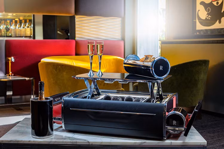 Không chỉ có thể, chiếc vali có võng treo bên sườn mà tự động mở ra để hé lộ hai hộp giữ mát sâm-panh được chế tạo từ sợi carbon và nhôm oxít hóa anốt màu đen. Chiếc vali cũng có lắp đặt đèn chiếu sáng và bốn chiếc khăn cốt-tông với chữ “RR” lồng vào nhau.