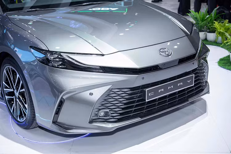Về mặt thiết kế, ngoại thất của Camry 2025 mang đường nét trẻ trung. Điểm nhấn ở phần đầu xe là cụm lưới tản nhiệt và mũi xe được thiết kế ấn tượng hơn. Phần đầu xe được thiết kế mở rộng sang hai bên. Cụm đèn chiếu sáng dạng LED thiết kế cách điệu.