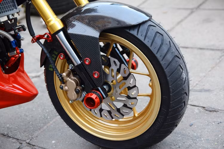 Dàn chân trước được trang bị chống đổ đồ chơi, đĩa Racingboy, mâm xe cũng được lên đời với màu vàng trung với cặp phuộc trước.