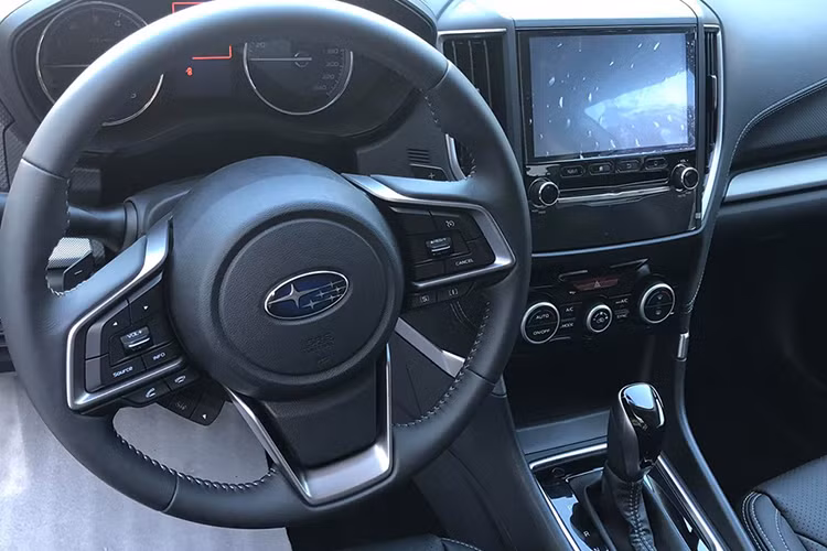 Bên trong nội thất, Subaru Forester có thiết kế không quá bóng bẩy. Vô-lăng bọc da tích hợp lẫy chuyển số thể thao, ghế trước chỉnh điện và nhớ hai vị trí. Hệ thống thông tin giải trí gồm màn hình cảm ứng 8 inch, tương thích Apple Car Play, các kết nối USB/AUX/Bluetooth, điều hòa tự động với cửa gió hàng ghế sau, khởi động bằng nút bấm.