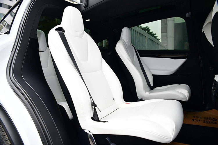 Vô-lăng của xe được bọc da, thiết kế 3 chấu tích hợp một số phím chức năng. Chiếc Tesal Model X P100D này có thiết kế 6 chỗ ngồi, tất cả đều được bọc da cao cấp màu trắng trùng màu ngoại thất. hai hàng ghế đầu có khả năng chỉnh điện. 2 ghế ở hàng thứ 2 thiết kế tách rời nhau tạo lối đi khá rộng xuống hàng thứ 3. Hàng ghế cuối dành cho 2 người ngồi với 2 khay để cốc đặt giữa.