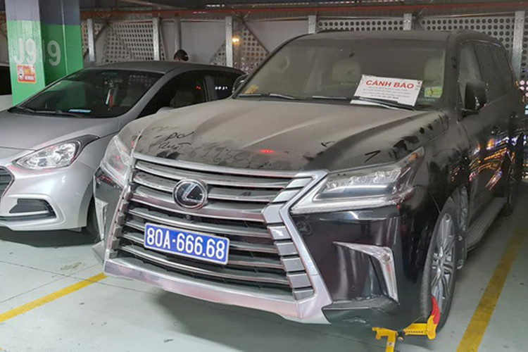 Những ngày qua, mạng xã hội Facebook lan truyền hình ảnh chiếc xe sang Lexus biển xanh 80A-666.68 bị khóa bánh, phủ đầy bụi nằm ở tầng 3 tại bãi giữ xe sân bay Tân Sơn Nhất khiến cộng đồng mạng xôn xao. Ngoài ra, trên kính xe còn được gắn bảng cảnh báo "Xe của quý khách tạm thời bị khóa bánh do đậu sai quy định. (Ảnh N.V.Q.).