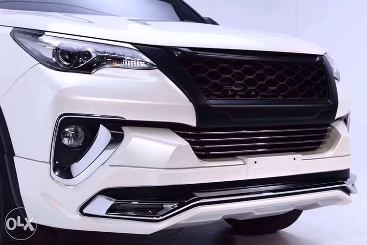 Chưa hết, chiếc Toyota Fortuner 2017 độ bodykit mới này còn được bổ sung cản va trước mở rộng với chi tiết mạ crôm dày dặn trong hốc đèn sương mù. Trên cản va trước còn xuất hiện dải màu đen tích hợp đèn LED định vị ban ngày. Trong khi đó, ở nắp capô có thêm gương chiếu hậu góc rộng giúp người lái quan sát tốt hơn.