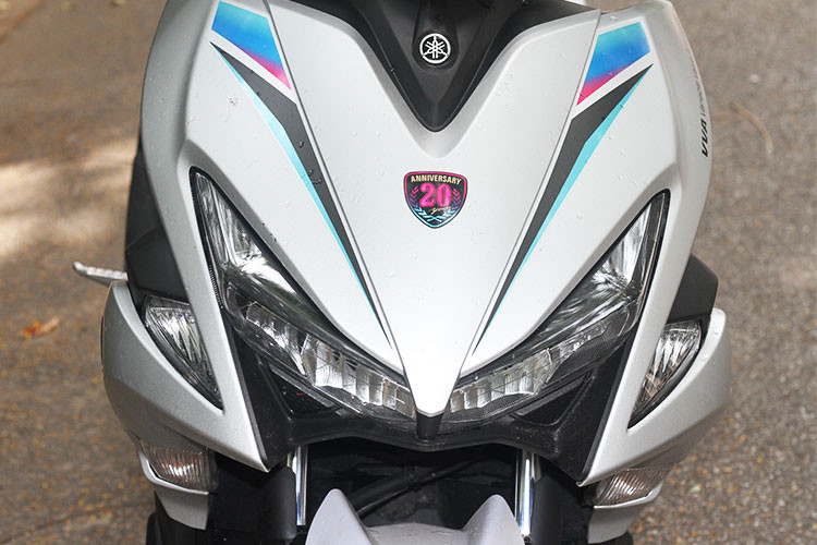 Phần đầu của chiếc xe được phối màu theo 3 tông trắng, đen và xanh da trời. Cách phối với các tông màu mới này mặc dù không mới nhưng lại có cảm giác khá lạ mắt trên dòng xe NVX 155, nhờ bộ tem kỷ niệm 20 năm của hãng xe máy Yamaha.