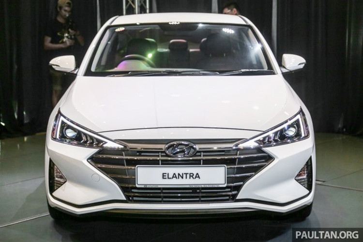 Hyundai Elantra 2019 sở hữu cụm đèn pha halogen thanh mảnh kéo dài lên tận nắp ca-pô, trong khi dải đèn định vị chiếu sang ban ngày dạng LED. Đèn sương mù lớn dạng tam giác nằm hai bên, phần cản trước mở rộng.