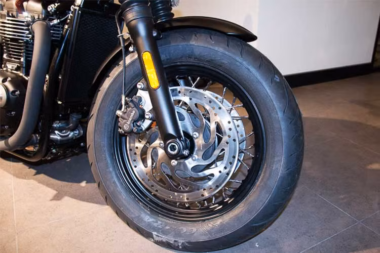 Không sử dụng cấu hình vành nan 19 inch bản mỏng cho bánh trước, Triumph đã trang bị cho Bobber Black vành 16 inch kèm lốp Avon Cobra 130/90 tương tự như bánh sau xe. Hệ thống phanh trước cũng được nâng cấp triệt để, gồm 2 đĩa phanh đường kính 310mm (Bobber thường chỉ có 1 đĩa, 2 piston), heo dầu Nissin 4 piston.