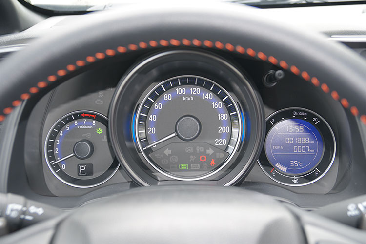 Phía sau vô lăng Honda Jazz 2018 là cụm đồng hồ lái analog đặc trưng những mẫu xe hạng B từ Honda. Trung tâm là đồng hồ tốc độ, bên trái nhỏ hơn là đồng hồ tua máy và bên phải là màn hình thông tin cung cấp các thông số vận hành. Điều đáng tiếc duy nhất, đây là màn hình tinh thể lỏng đơn sắc khá nhàm chán, nếu đây là màn hình LCD tương tự thị trường Mỹ thì nội thất Jazz sẽ thêm phần hiện đại hơn.