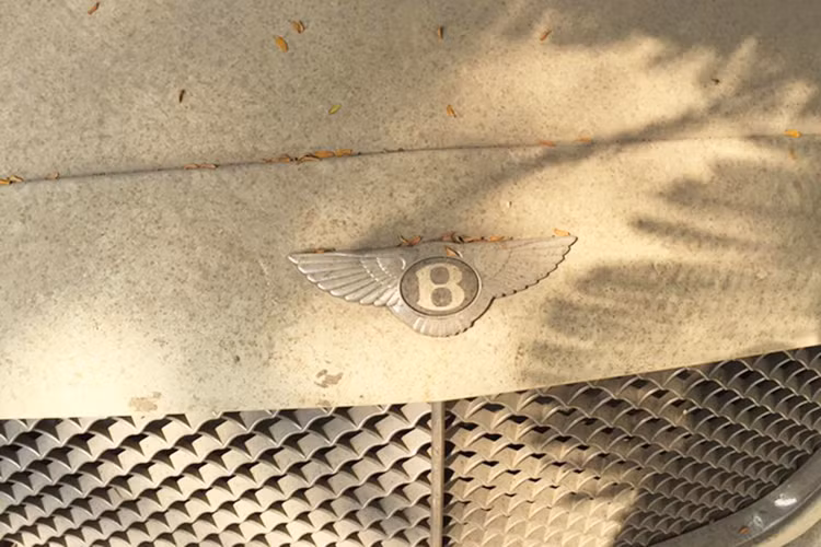 Chính bởi vì không được mang ra sử dụng trong một thời gian dài, nên chiếc xe Bentley Continental Flying Spur đời cũ này đóng một lớp bụi dày đặc đến nỗi người ta không thể nhìn thấy nội thất bên trong qua lớp kính chắn gió. Gỡ bỏ lớp bụi phủ từ đầu tới tận cuối đuôi xe có thể thấy đây là một chiếc xe màu trắng đeo biển kiểm soát Hà Nội.