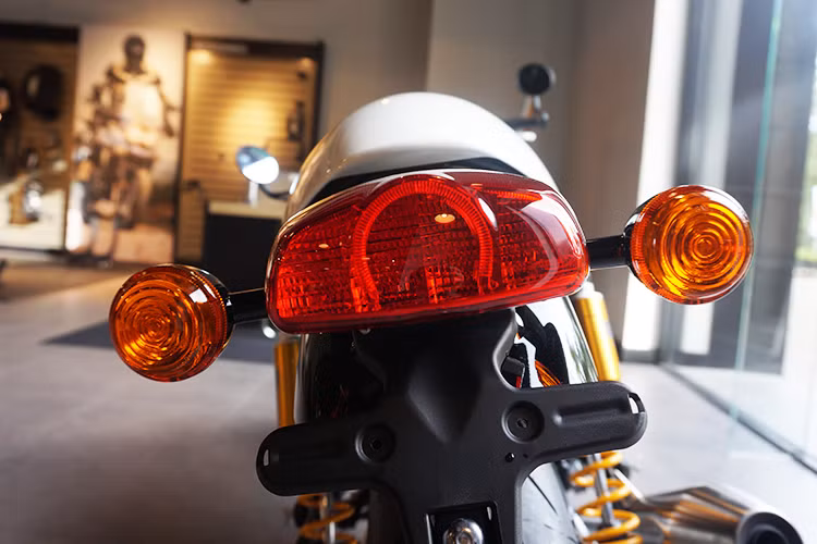 Nằm ở cùm công tắc bên phải của xe chỉ có nút đề, tắt máy và đặc biệt là nút bật đèn tín hiệu khẩn cấp. Bên cùm công tắc trái là những nút điều khiển để lựa chọn các chế độ lái, cũng như xi-nhan và còi... Đèn hậu của Thruxton R có thiết kế đơn giản, giống dòng xe Bonneville T120 với chóa đèn hậu lớn hơn nhiều, rộng gần ngang so với dè sau của chiếc xe.