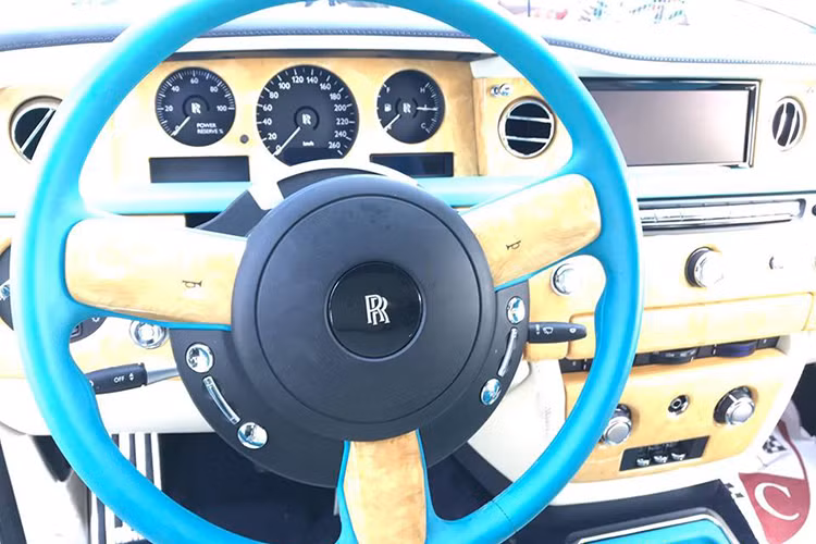 Chưa hết, toàn bộ bảng táp-lô và bảng điều khiển trung tâm của chiếc xe siêu sang này còn được ốp gỗ quý màu vàng nhạt với đường kẻ màu xanh ngọc đẹp mắt. Đây có thể xem là chiếc Rolls-Royce Phantom có nội thất "sexy" nhất tại Việt Nam tính đến thời điểm hiện tại.