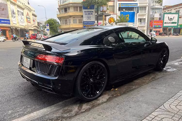 Nguyên bản chiếc siêu xe Audi R8 V10 Plus mà ông Đặng Lê Nguyên Vũ mới mua sở hữu màu đỏ, nhưng khi xuất hiện tại quận 5, Tp.HCM, xe đã được dán lại màu đen, điểm nhấn chính là nóc xe dán trắng. Thâ xe hai bên dán chứ UN, phong cách mới trên mọi chiếc xe của Qua Vũ.