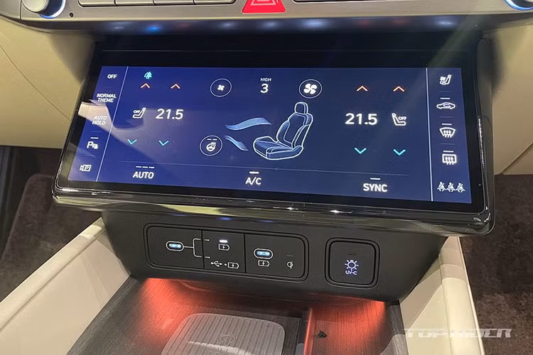 Bên dưới cửa gió là hàng nút bấm cơ học, màn hình cảm ứng 10,25 inch để chỉnh điều hòa, các cổng USB, sạc điện thoại không dây và ngăn chứa đồ có nắp che.