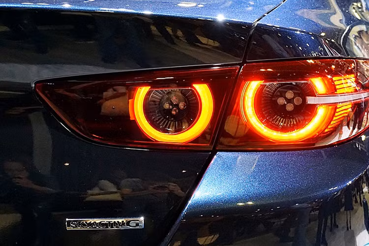 Bên dưới lưới tản nhiệt xuất hiện hốc gió hẹp, cụm đèn sương mù nhỏ và hai góc cản trước lồi ra. Phía sau, cuả Mazda3 2019 là ở cụm đèn hậu với 4 chóa hình tròn. Trong khi đó, nắp cốp sau lại đi kèm cánh gió nhỏ và tích hợp logo Mazda ở giữa. Bên dưới cản sau là 2 ống xả hình tròn.