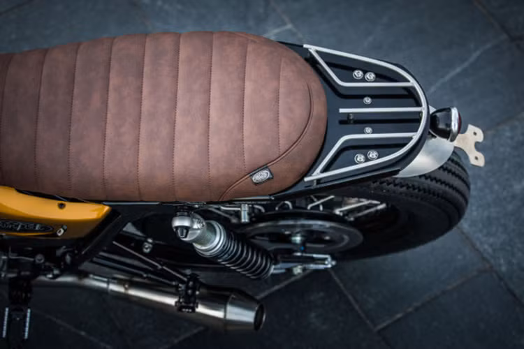Yên xe nguyên bản được loại bỏ gù, ốp và thay vào đó là yên bọc da nâu chế tác thủ công tinh tế. Bên cạnh đó nó còn có thêm tay xách nhỏ phía sau cực kỳ hợp lý.
