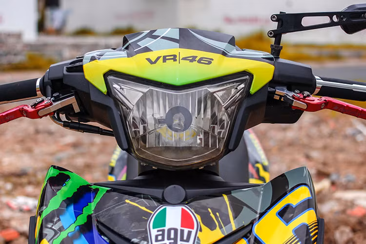 Ngay từ cái nhìn đầu tiên, siêu phẩm 150 phân khối này đã tạo ấn tượng sâu sắc với bộ tem đua MotoGP. Hai bên yếm xe là những chi tiết hoa văn sặc sỡ đi kèm số đua 46 của tay đua huyền thoại Valentino Rossi nằm chính giữa. Dàn đèn pha của xe được chủ nhân giữ nguyên bản.