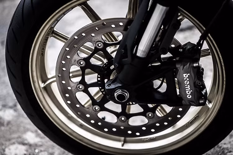 Trên mẫu xe này, hệ thống phanh trước sau của xe là loại Brembo và cặp vành 10 nan của phiên bản Scrambler Icon và Full Throttle cũng vẫn được giữ nguyên trên Cafe Racer. Tuy nhiên chiếc xe đã có mâm sơn màu vàng nổi bật hơn và sử dụng lốp Pirelli Diablo Rosso (120/70 ZR 17 ở phía và 180/55 ZR17 ở phía sau) như dòng sportbike 959 Panigale.