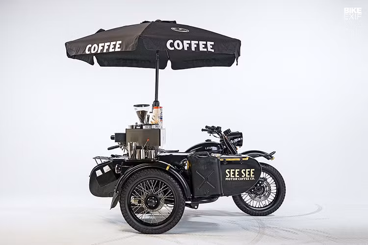 Ural Coffee Cart – See See là phiên bản độ cực kỳ độc đáo với phong cách SiderCar từ mẫu xe Ural cổ điển, đây là một “quán cafe di động” lý tưởng dành cho những người yêu thích xe cộ. Bản độ được thực hiện bởi xưởng độ See See, xe được lắp đặt thêm túi khí an toàn, bồn rửa tay, tủ giữ nhiệt, máy xay cafe, hệ thống cấp điện…Tất cả những trang bị này chỉ khiến bản độ nặng thêm 50kg. Xe vẫn có thể hoạt động một cách bình thường và được dùng để bán cafe di động.