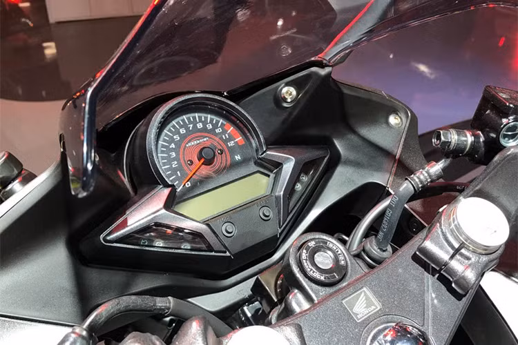 Cùng với đó, cụm đèn pha của Honda CBR250R đã được trang bị hệ thống đèn pha và đèn định vị LED. Bảng đồng hồ của xe thiết kế đơn giản với đồng hồ dạng kim truyền thống đo vòng tua máy, phía dưới là màn hình lcd cỡ nhỏ chỉ tốc độ, thông số, báo xăng... cùng đèn báo.