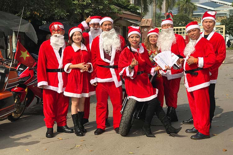 Những ông và bà già Noel mang đến bệnh viện K Tân Triều 60 suất quà, mỗi suất trị giá hơn 500 nghìn đồng bao gồm bánh, sữa và tiền mặt. Nhã Phương (áo đỏ) cho biết năm nào cũng cùng chồng đi tặng quà trong dịp Noel. Mọi khi, vợ chồng Phương đi chiếc xe Sidecar nhưng hôm nay thì chạy một chiếc xe bình thường để tranh thủ đi làm.