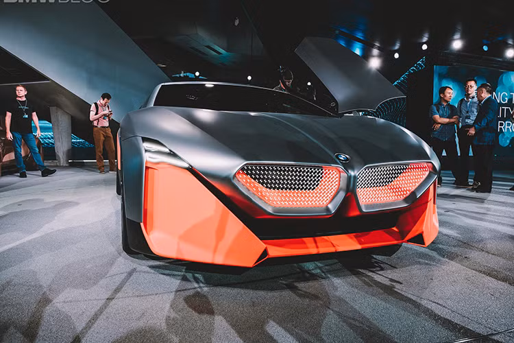 Thậm chí là nhìn từ một số góc độ, Vision M Next còn có một dáng vẻ rất chất “Lamborghini Gallardo.” Phần mũi xe nằm thấp, có trang bị đèn pha Laser Wire, cửa cánh chim, ốp ngưỡng cửa bằng sợi carbon, bộ la-zăng hợp kim với họa tiết chấu hình chữ Y và một lớp sơn vô cùng sống động, kết hợp màu cam Thrilling Orange và kim loại bạc Cast Silver.