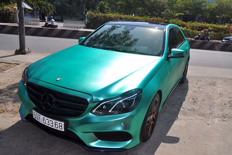 Chiếc Mercedes E250 AMG được chủ nhân “độ nhẹ” với lớp sơn xe được dán phủ bằng đề-can crôm màu xanh độc đáo biến màu theo từng góc độ nhìn. Nếu chỉ nhìn lướt qua, bạn sẽ khó có thể nhận ra đây là chiếc xe được dán đề can.