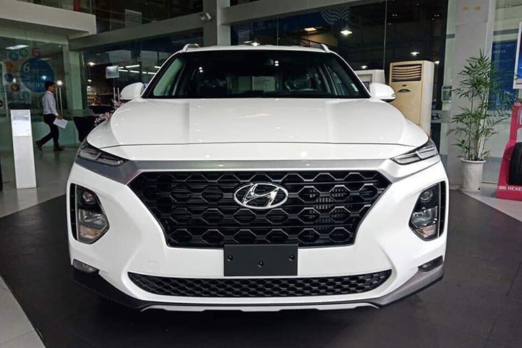 Phiên bản Hyundai SantaFe 2019 mới xuất hiện tại đại lý lần này có màu sơn trắng, phiên bản tiêu chuẩn với các đặc điểm dễ nhận ra như mâm đúc 18 inch chứ không phải loại 19 inch, nóc xe không có cửa sổ trời. Phiên bản trưng bày là bản động cơ dầu 2.2D.