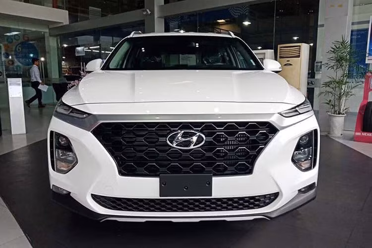 Phiên bản Hyundai SantaFe 2019 mới xuất hiện tại đại lý lần này có màu sơn trắng, phiên bản tiêu chuẩn với các đặc điểm dễ nhận ra như mâm đúc 18 inch chứ không phải loại 19 inch, nóc xe không có cửa sổ trời. Phiên bản trưng bày là bản động cơ dầu 2.2D.