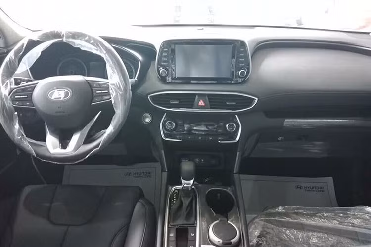 Bên trong của SantaFe 2019 bản tiêu chuẩn thiếu đi vài tính năng cao cấp như đồng hồ công tơ mét kỹ thuật số, thay vào đó là dạng analog truyền thống. Xe cũng chỉ sử dụng phanh tay cơ thông thường chứ không phải là loại phanh tay điện tử đi kèm tính năng Autohold.