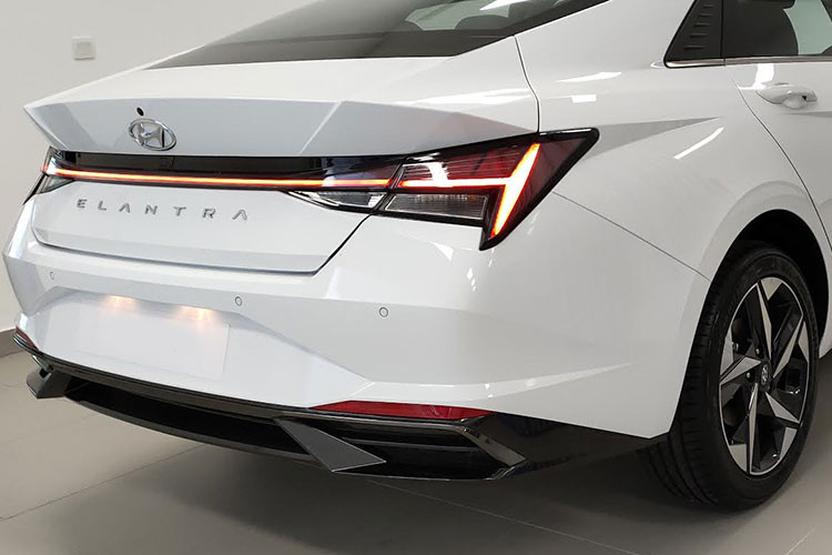 Dáng vẻ coupe hiện rõ khi quan sát từ đuôi xe Hyundai Elantra 2021 với phần kính chắn gió kéo dài xuống nắp ca-pô. Trung tâm là dải đèn LED nối liền cụm đèn hậu với đồ hòa bắt mắt là chi tiết cải tiến so với "người tiền nhiệm". Cản sau của Hyundai Elantra mới có thiết kế khí động học, ống xả giả 2 bên giúp chiếc sedan này cân đối hơn.