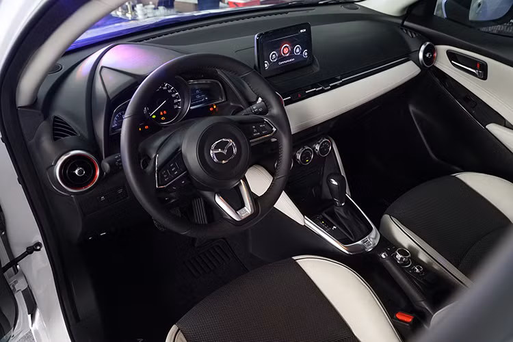 Bên trong, thiết kế vô-lăng trên Mazda2 đời 2018 cũng được lấy cảm hứng từ những người anh em Mazda CX-5, Mazda6, Mazda3 nên trông góc cạnh, mạnh mẽ hơn. Xe cũng đã được tích hợp 2 tính năng khá thú vị là lẫy gẩy số sau vô-lăng và hệ thống kiếm soát hành trình Cruise Control. Đây là hai tính năng khá hữu dụng nhưng lại hiếm khi xuất hiện trên một mẫu xe hạng B như Mazda2.