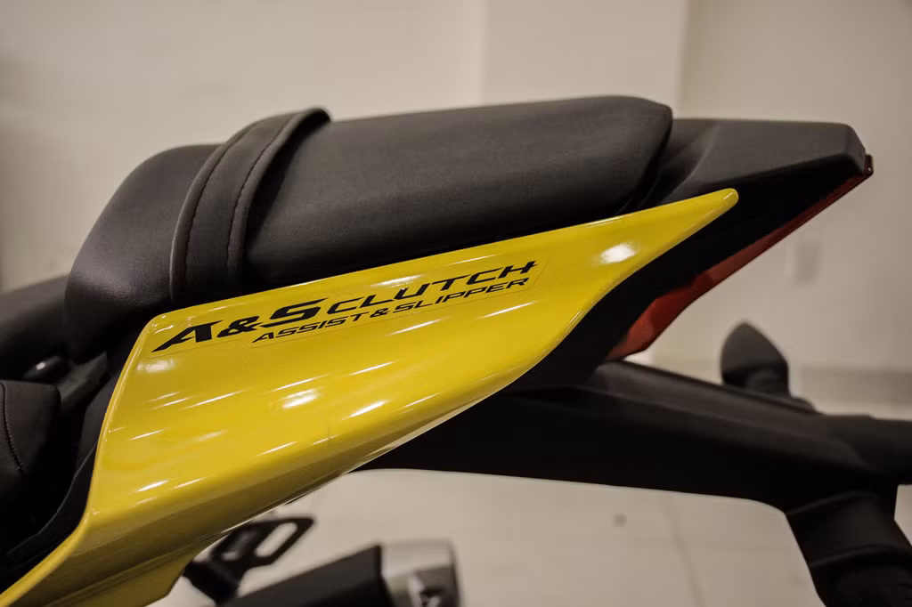 Khác với ký hiệu LC4V (Liquid Cool 4 Valve) trên phiên bản trước, phần đuôi Yamaha R15 2018 vàng racing có dán dòng chữ Assist &amp; Slipper Clutch. Đây cũng là trang bị mới nhất trên R15 thế hệ 2018, hỗ trợ chống trượt bánh khi dồn số khá phổ biến trên các dòng xe phân khối lớn.