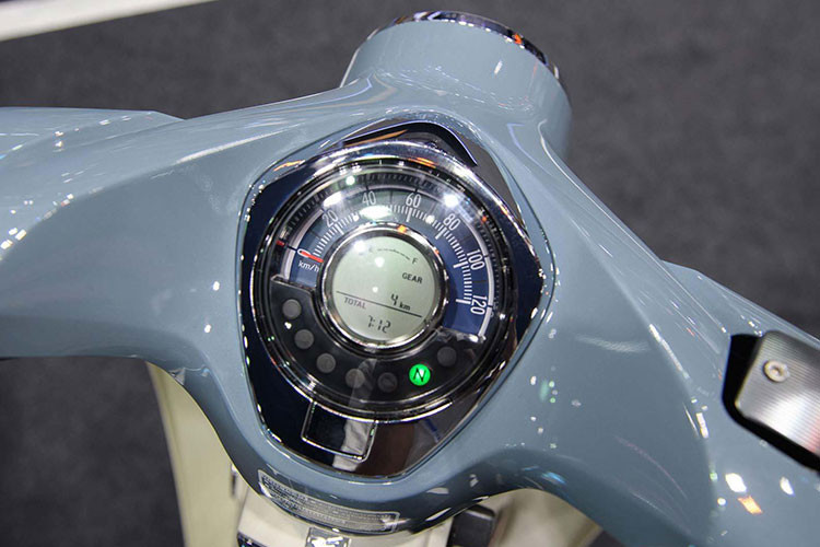 Cụm đồng hồ dạng tròn quen thuộc trên các thế hệ Honda Super Cub nhưng được làm mới, pha lẫn hiện đại và cổ điển. Đồng hồ vẫn hiển thị những thông số đơn giản nhưng được bổ sung thêm màn hình điện tử hiện đại, sự pha trộn này tạo cảm giác gần gũi và cá tính.