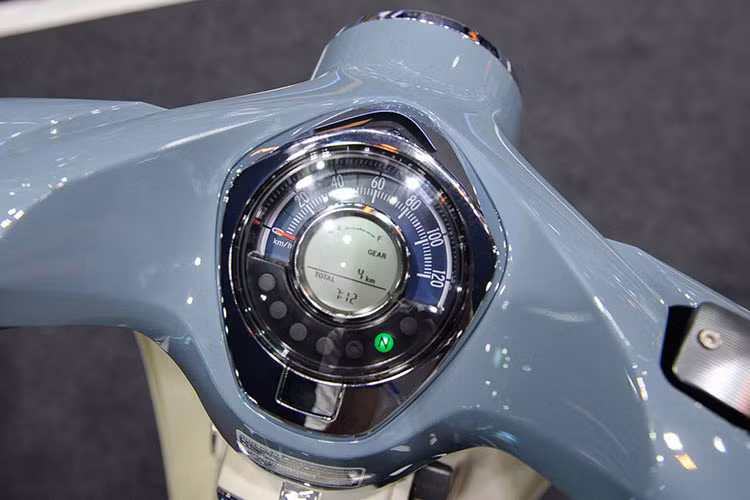 Cụm đồng hồ dạng tròn quen thuộc trên các thế hệ Honda Super Cub nhưng được làm mới, pha lẫn hiện đại và cổ điển. Đồng hồ vẫn hiển thị những thông số đơn giản nhưng được bổ sung thêm màn hình điện tử hiện đại, sự pha trộn này tạo cảm giác gần gũi và cá tính.