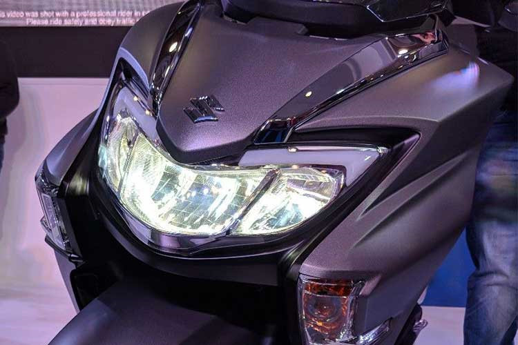 Mang "hơi thở" của các đàn anh xe ga cỡ lớn, Suzuki Burgman 125 2018 mới có thiết kế mới cơ bắp và ấn tượng từ mọi góc nhìn. Đầu xe sở hữu bộ đèn full LED kiểu mới với 2 dải viền kim loại phía trên đẹp mắt. Kính chắn gió được trang bị cũng làm tăng thêm nét thể thao cho mẫu maxiscooter mới này.