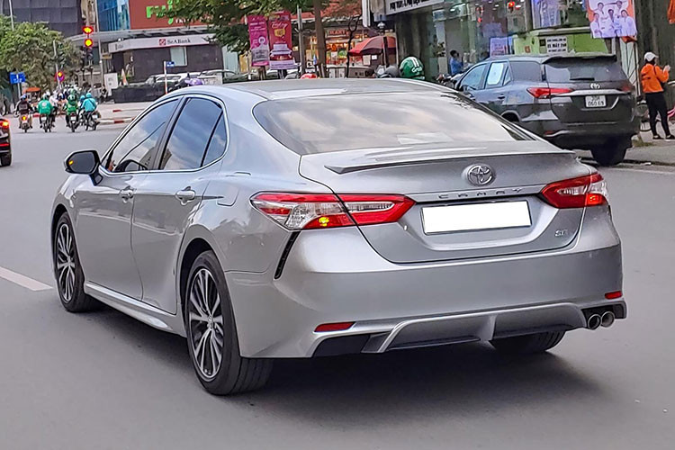 Đèn pha của mẫu xe sedan Toyota Camry SE 2021 nhập Mỹ này thu gọn cùng đèn định vị là dải đèn LED sắc sảo. Bộ mâm 18 inch thiết kế thể thao pha 2 màu đen bạc. Đuôi xe có các cánh gió gắn cố định cùng ống xả kép đặt bên phải. Cản sau thể thao kết hợp với cánh chia gió nhỏ. Bên dưới là cụm đèn hình mang cá chạy dọc.