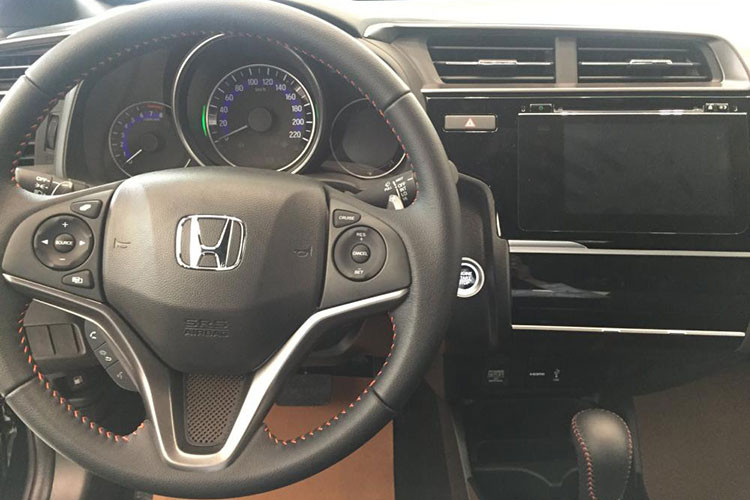 Bảng điều khiển trung tâm của xe với màn hình cảm ứng 7 inch, hỗ trợ kết nối smartphone, HDMI hay USB. Camera lùi cũng được hiển thị trên màn hình này. Bản RS có điều hòa tự động. Về mặt tiện ích, Honda Jazz cũng rất phong phú với điều hòa tự động, ổ cắm 12V, khe USB, nhiều hộc đựng đồ bố trí khắp khoang xe...